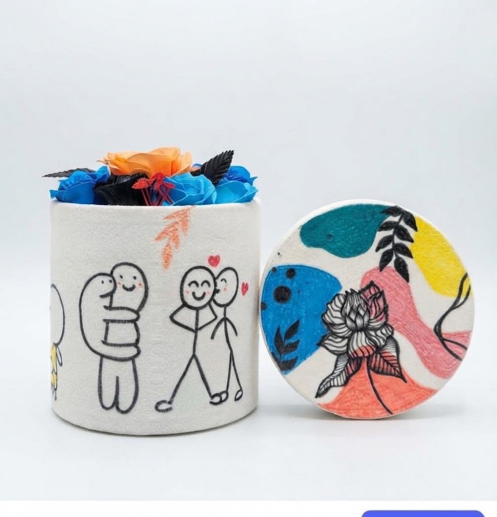 A hand-painted keepsake box covered in doodles with an artificial flower bouquet
